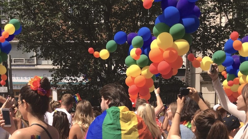 People watching Brighton Pride with rainbow balloons